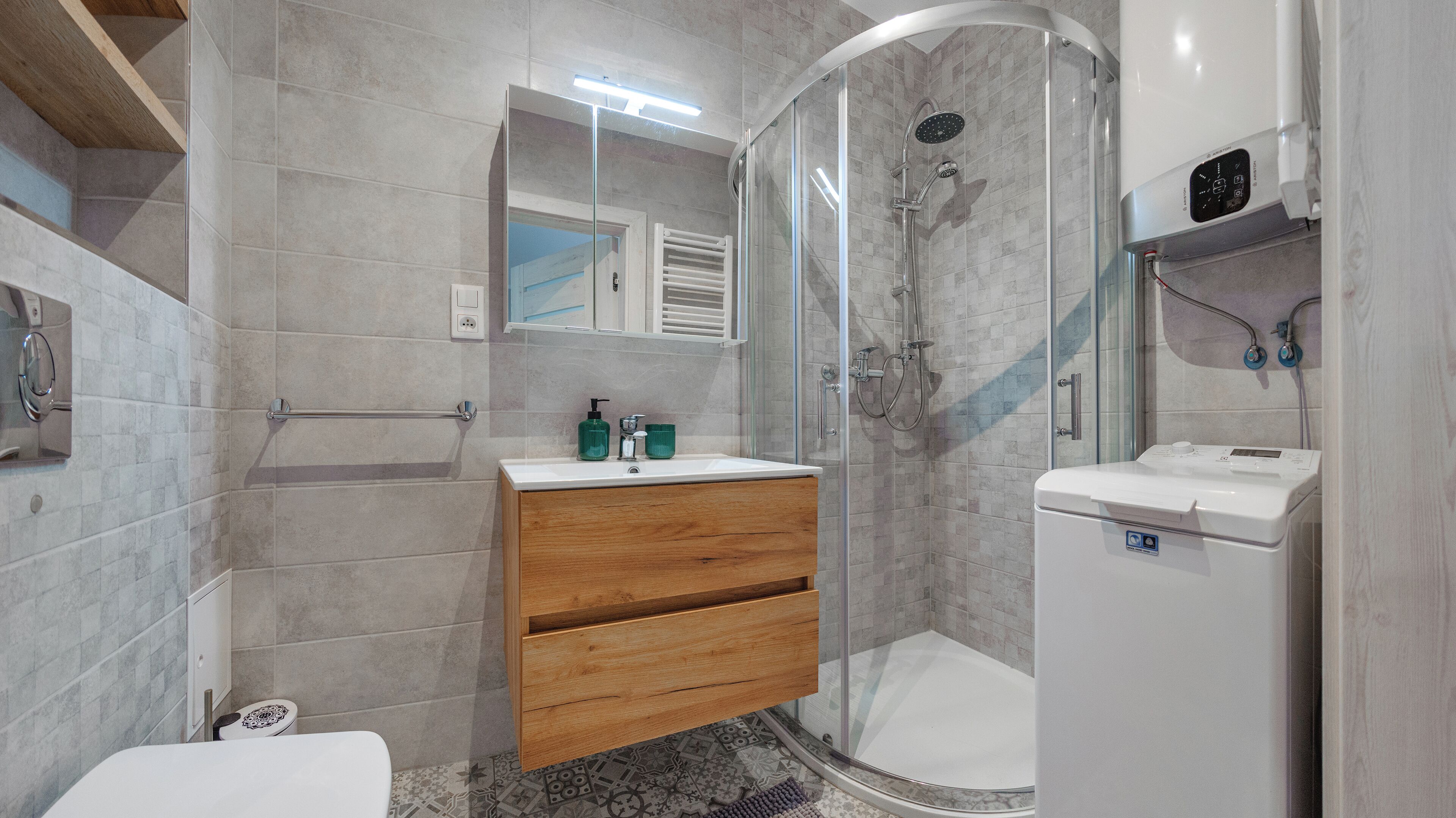 Un baño moderno con cabina de ducha de vidrio, tocador de madera y un inodoro blanco.
