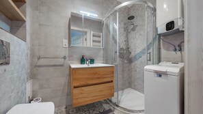 A modern bathroom with a glass-enclosed shower, a wooden vanity, and a white toilet. - Apartamenty Sun & Snow Marynarska Rowy (Ustka)