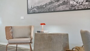 Una stanza con una sedia moderna, un tavolino con una lampada rossa e un cesto intrecciato.