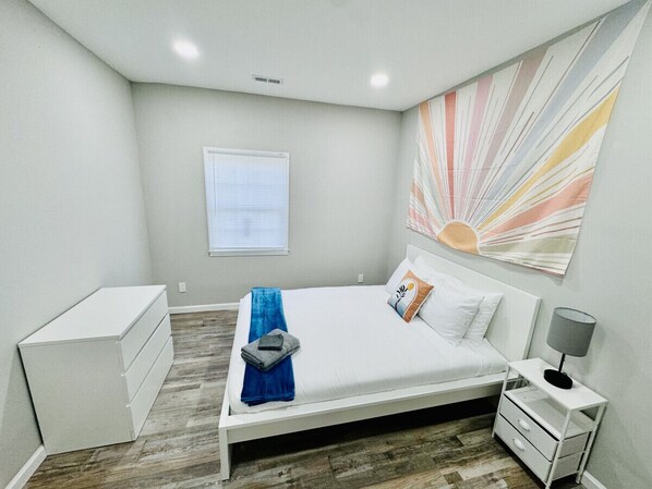 A bedroom with a bed, bedside tables, a dresser, and a window.