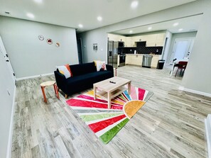 Uma sala de estar moderna com um sofá preto, uma pequena mesa de centro de madeira e um tapete colorido.
