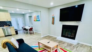 A modern living room with a black sofa, a small wooden table, and a colorful rug.