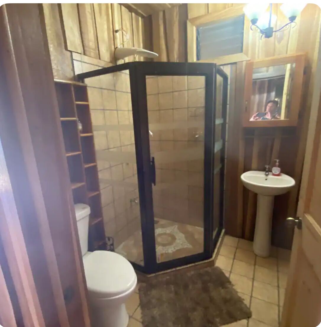 A bathroom with a shower enclosure, toilet, sink, and a mirror.
