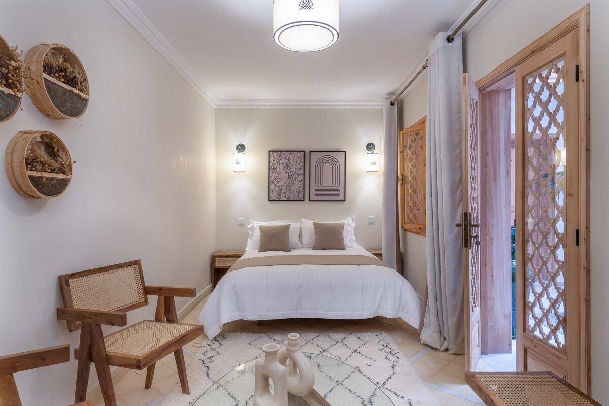 A bedroom with a bed, a chair, a nightstand, wall-mounted baskets, and a door with a lattice design.
