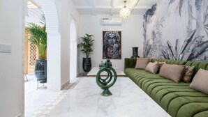 Ein modernes Wohnzimmer mit einem grünen Sofa, einem Marmor-Couchtisch und einem großen Gemälde an der Wand.