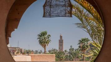 A view through a circular window of a building with a tall tower and palm trees.