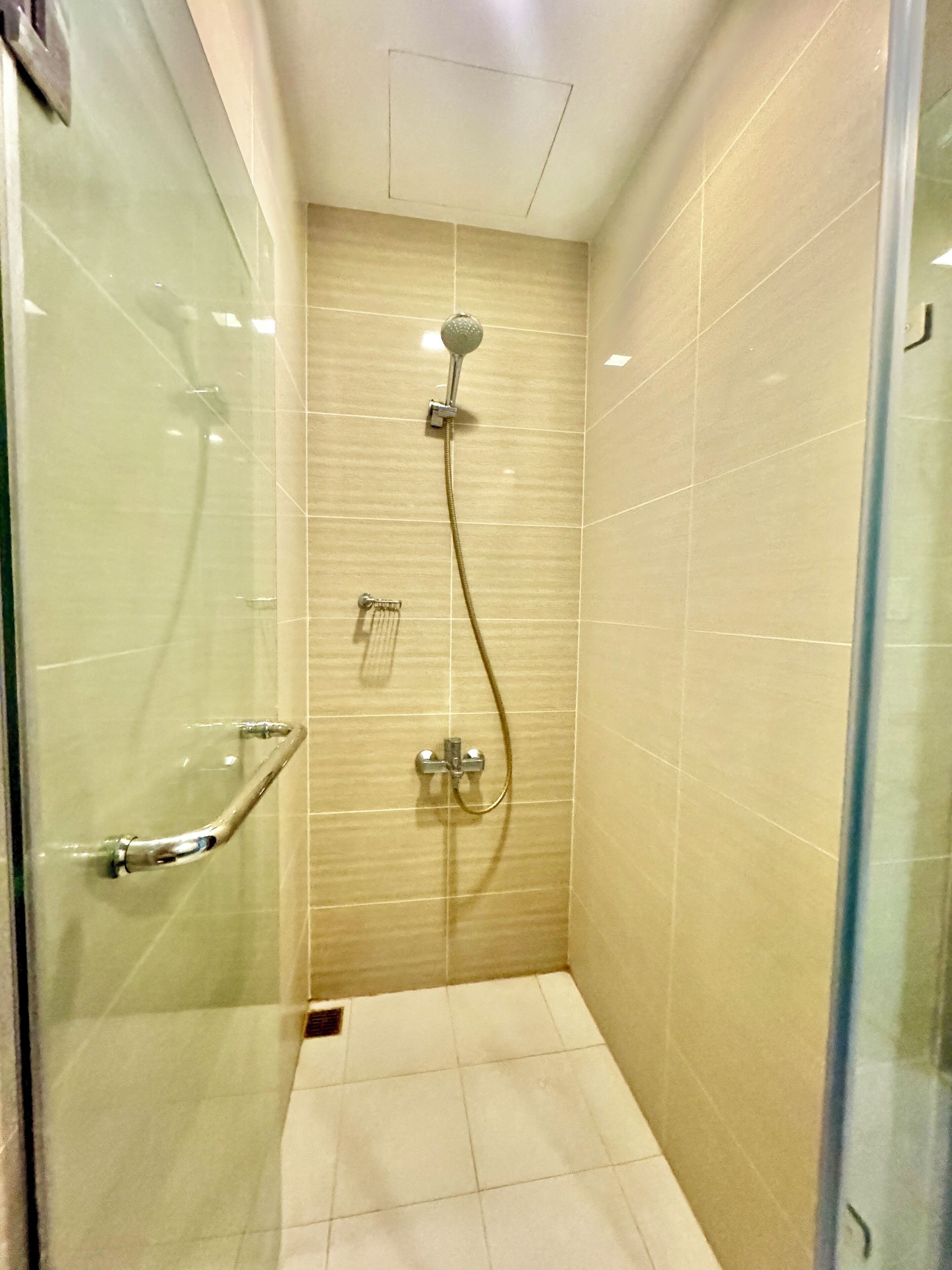 Un pequeño espacio de ducha con azulejos, equipado con un cabezal de ducha y un grifo de mano.