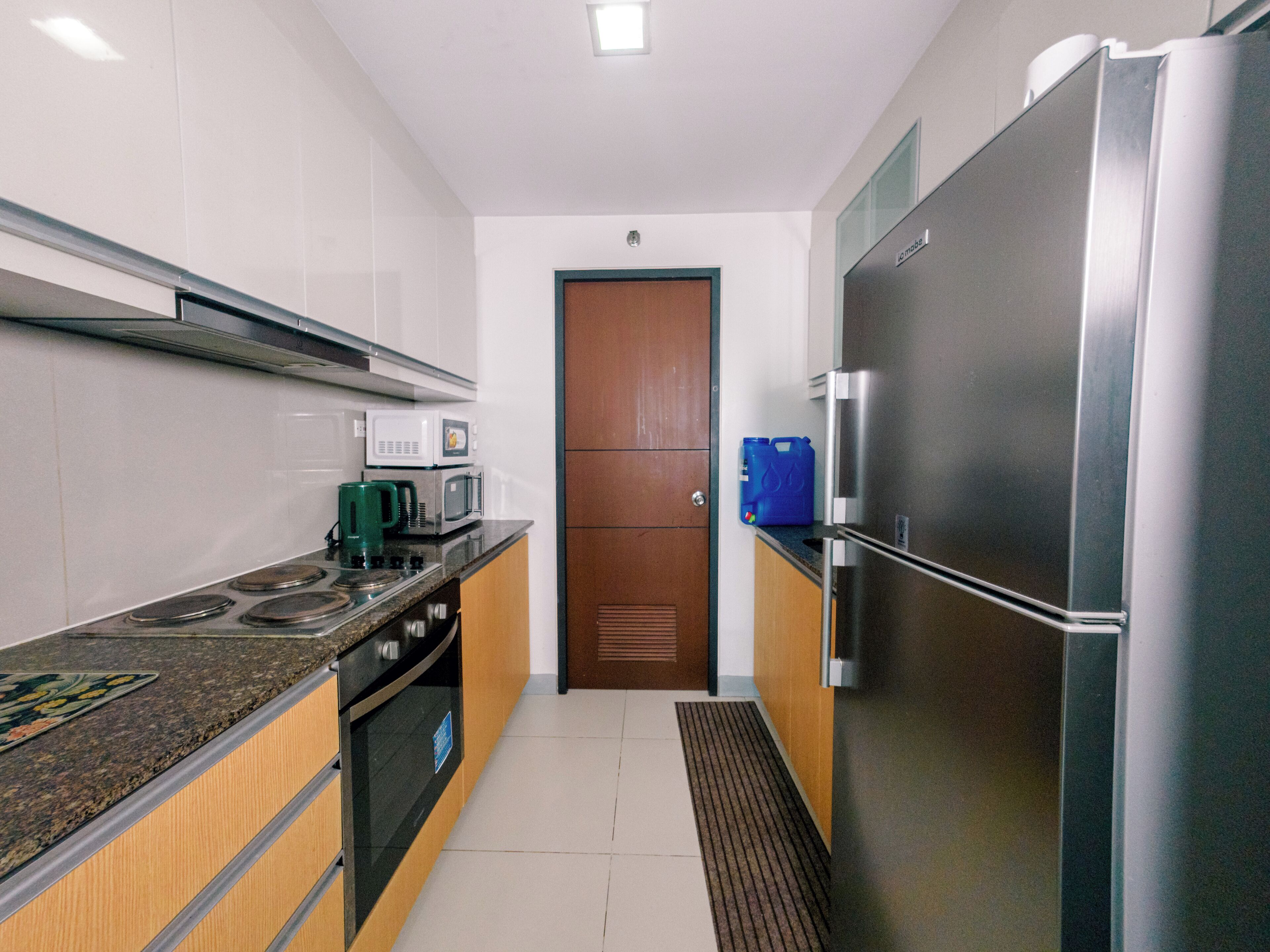 A modern kitchen with stainless steel appliances, a microwave, a coffee maker, and a blue water dispenser.