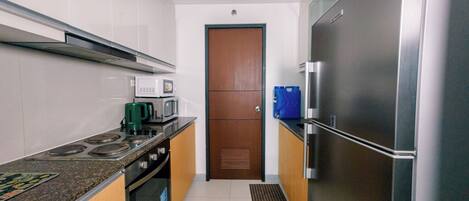 A modern kitchen with stainless steel appliances, a microwave, a coffee maker, and a blue water dispenser.
