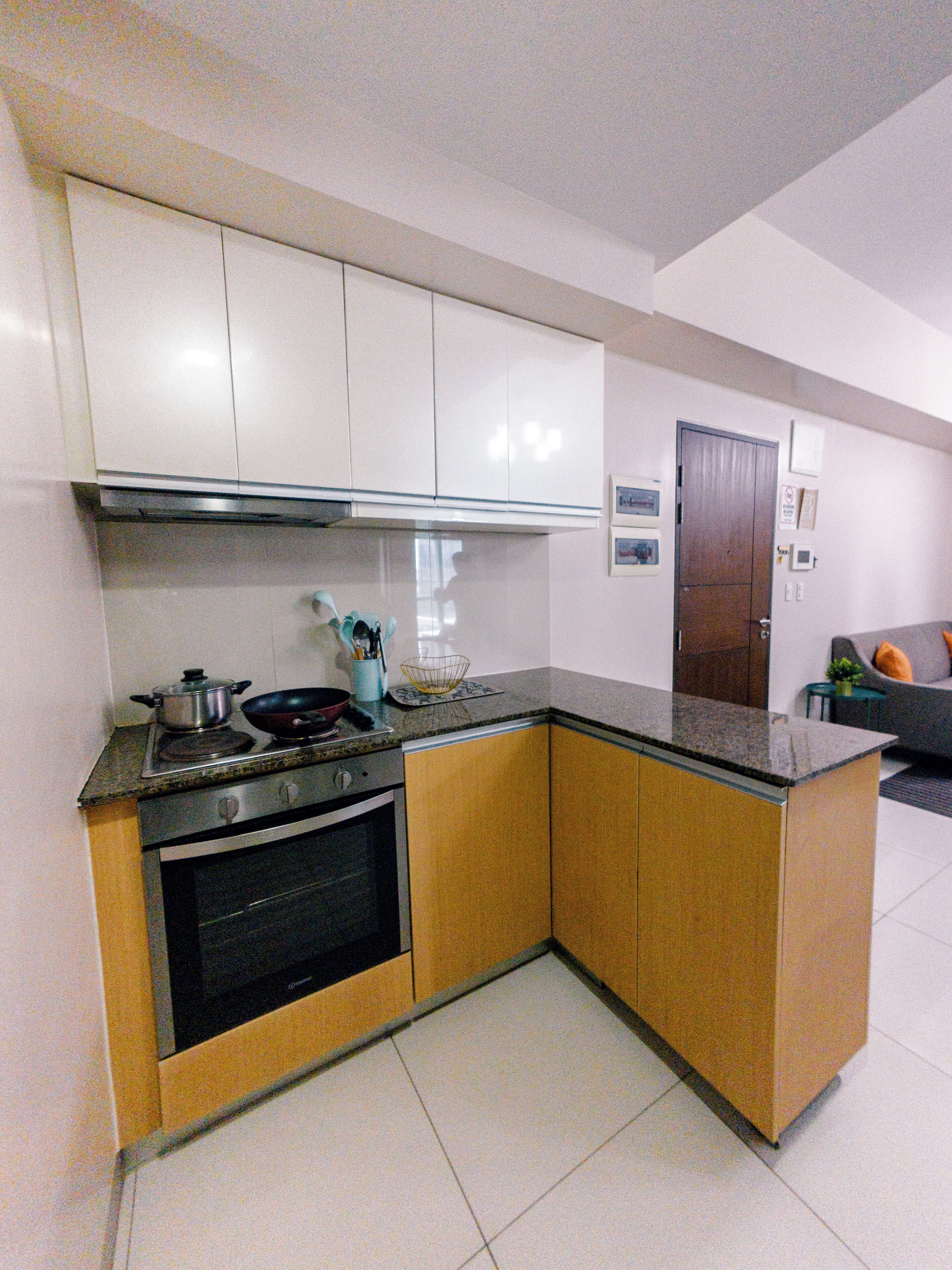 A compact kitchen with white cabinets, a stove, and a sink.