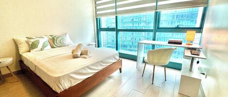 A modern hotel room with a large bed, a desk, and a chair.