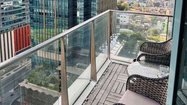 A balcony with a view of a cityscape, featuring modern buildings and a clear sky. - Cozi Uptown Executive Suite BGC (Taguig)