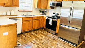 Une cuisine avec des meubles en bois, des appareils électroménagers en acier inoxydable, une fenêtre et un lave-vaisselle.