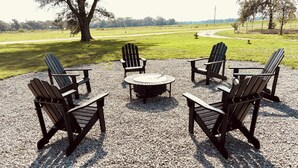 Une terrasse en gravier avec des chaises Adirondack et une table ronde.