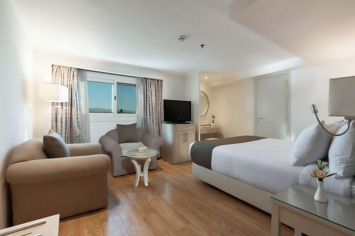 Camera d'albergo moderna con un letto grande, due divani, un tavolino, una televisione e un armadio.