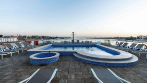 Un espace piscine avec des chaises longues et une vue sur les gratte-ciel de la ville.