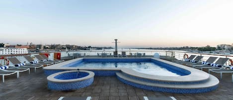 Una piscina al aire libre, sillones reclinables de piscina