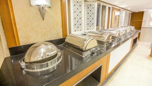 A buffet setup with multiple serving stations, a wall-mounted light fixture, and patterned decorative panels. - Orient Sun Times Nile Cruise-Every Monday from Luxor for 04 & 07 Nights - Every Friday From Aswan for 03 Nights (Luxor)