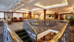 Un hall d’hôtel doté d’un magnifique escalier, de rampes décorées et d’un lustre.