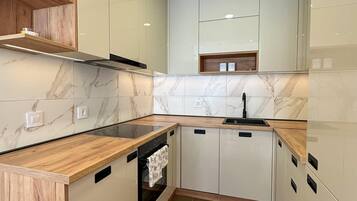 Una cocina moderna con encimeras de mármol, estanterías de madera y armarios empotrados.