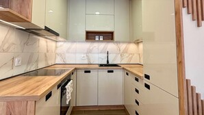 A modern kitchen with wooden cabinetry, a marble backsplash, and a built-in oven. - I&I 3 Bedrooms Apartment (Kragujevac)
