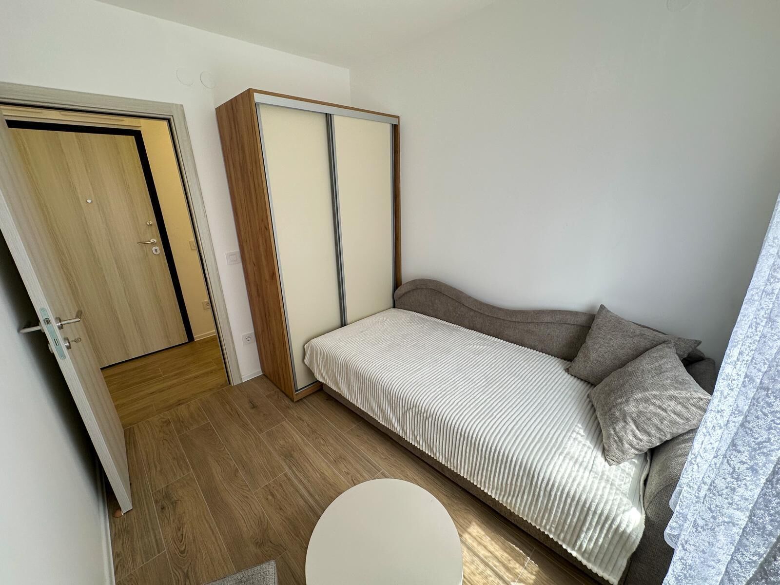 A bedroom with a bed, a wardrobe, and a round table.