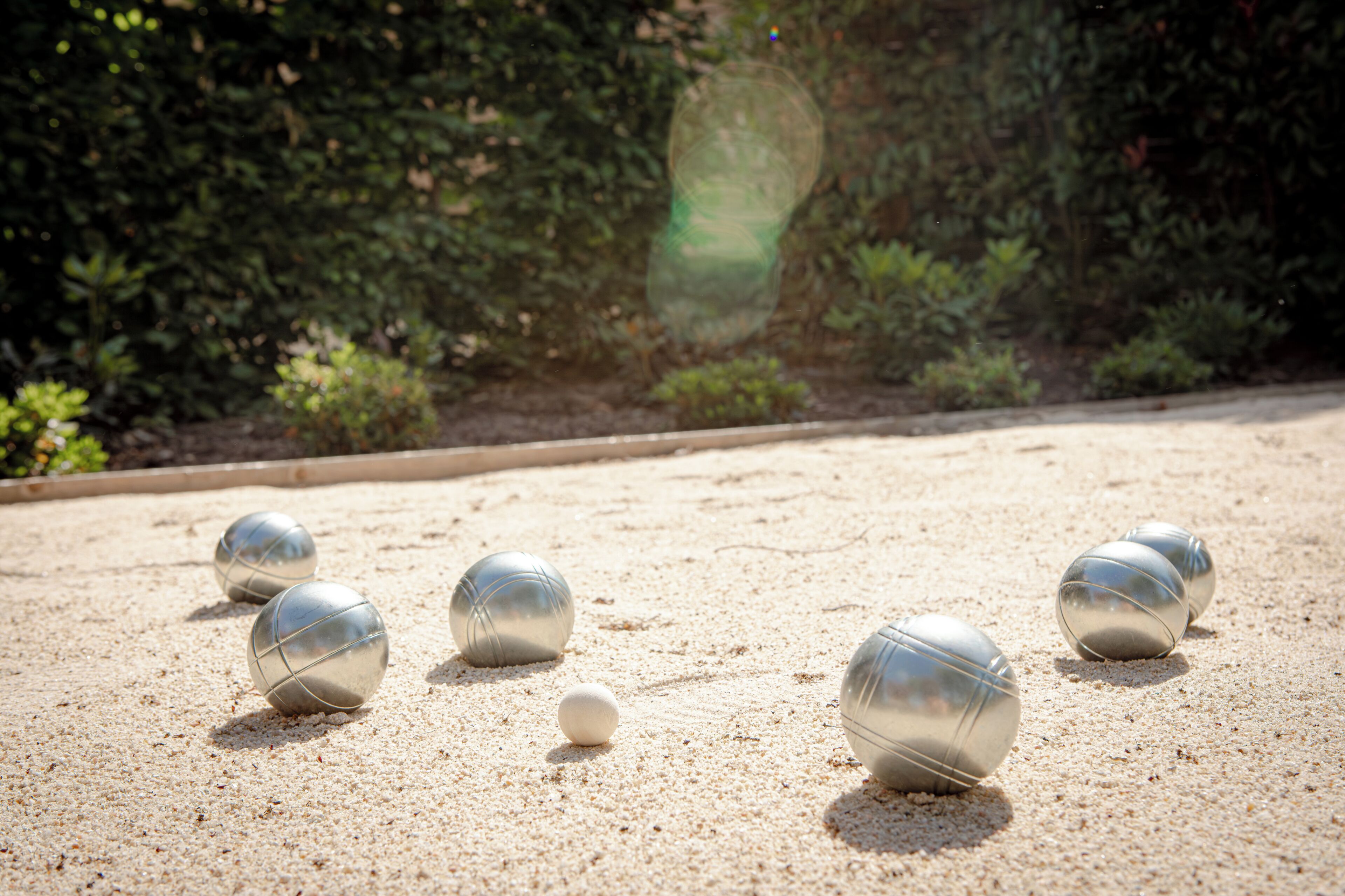 A sand court with four metallic balls and one white ball.