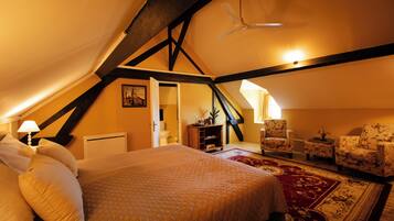 A bedroom with a large bed, a ceiling fan, a red carpet, and a wooden chair.