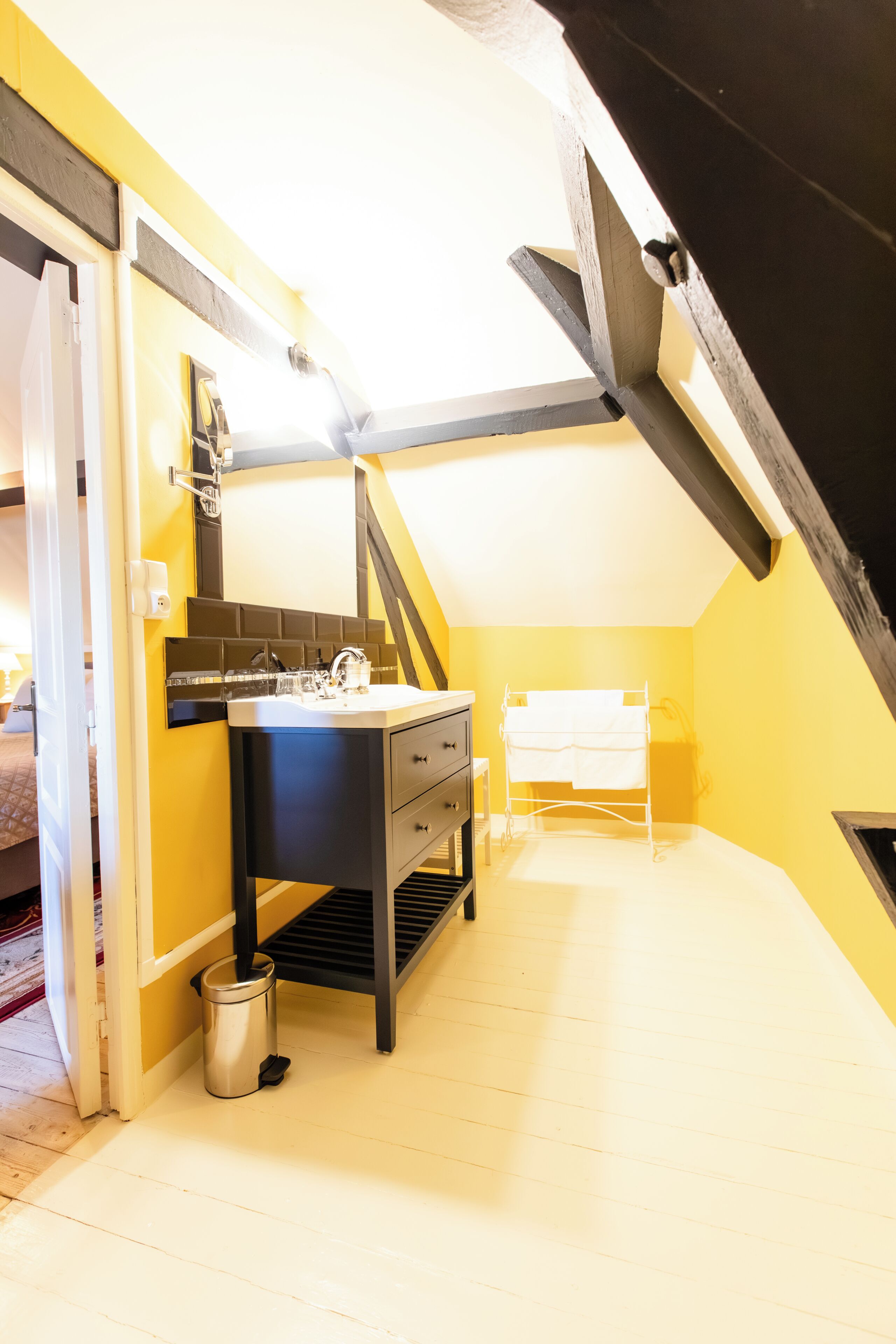 A small, narrow room with a white sink, a mirror, and a black cabinet.