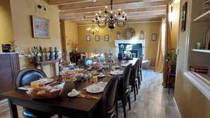 Zona pranzo con un tavolo lungo apparecchiato per la colazione, con diversi piatti e bevande.