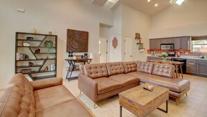 Un salon spacieux avec un grand canapé d’angle en cuir marron, une table basse en bois et une bibliothèque.