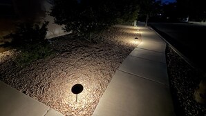 Un sentier pavé de petits cailloux, avec un petit trou, qui mène à un bâtiment.