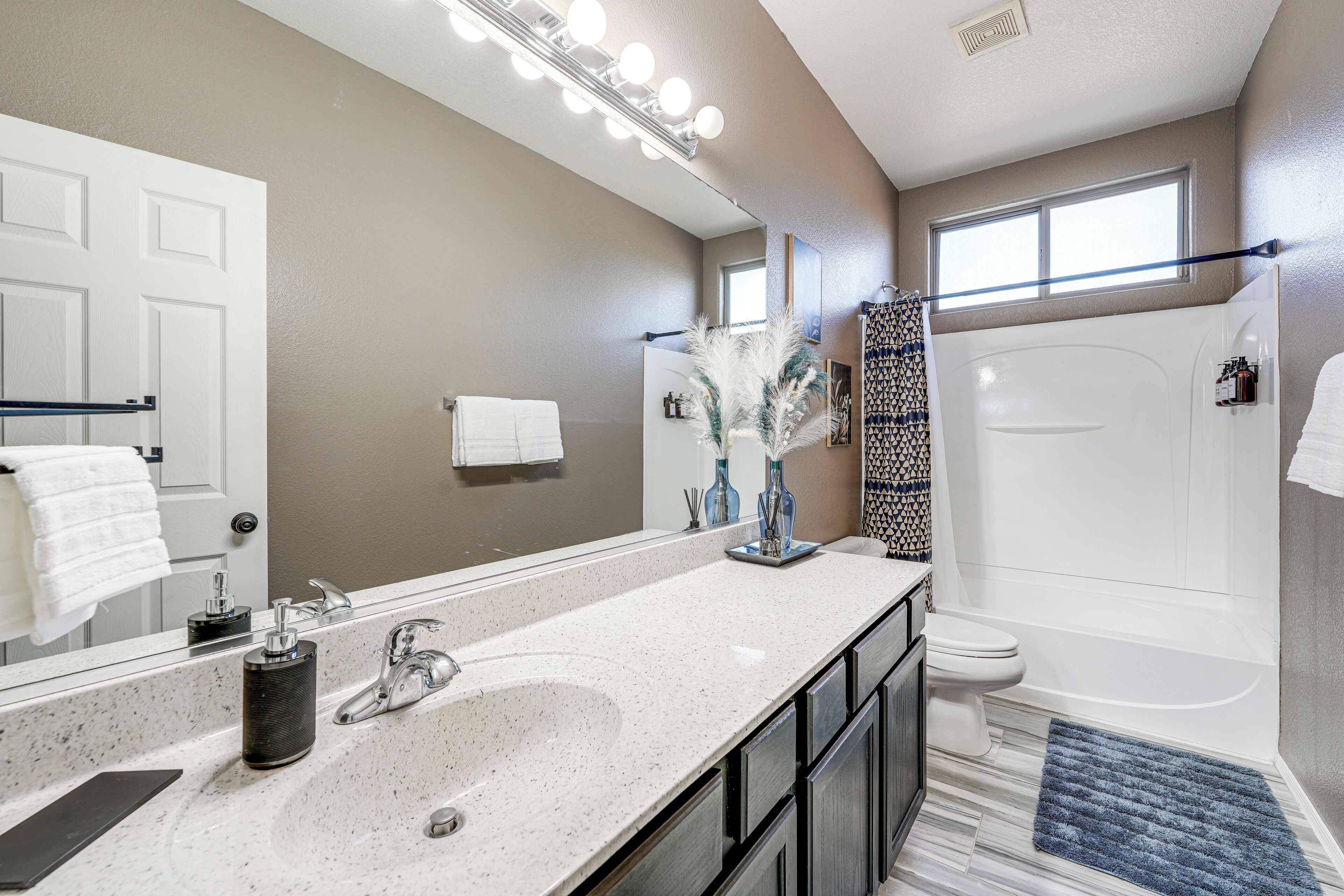 A modern bathroom with a large mirror, a sink, a toilet, and a shower.