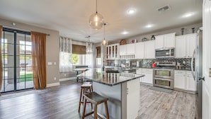 Une cuisine spacieuse dotée d’un grand îlot central, de meubles blancs et d’appareils électroménagers modernes.