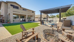 Une maison moderne dotée d’un patio aménagé avec des meubles d’extérieur, un foyer et une pergola.
