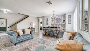 Un salon spacieux avec un grand canapé, un coin repas agrémenté d’un mur en briques et un escalier.