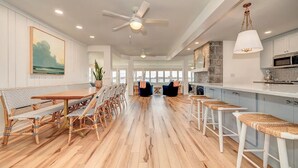 A spacious kitchen with a long countertop, white cabinets, and a stone accent wall. - Colcord Point Sunset Cottage and Guest Cottage (Okoboji)