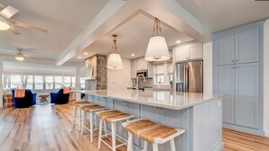 A modern kitchen with a large island, bar stools, and a stone accent wall. - Colcord Point Sunset Cottage and Guest Cottage (Okoboji)