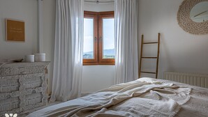 Une chambre à coucher avec un lit, une commode, une fenêtre avec des rideaux, un miroir et une échelle.