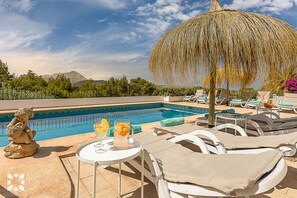 A poolside area with lounge chairs, a table with drinks, and a decorative umbrella. - Villa MOBA by Abahana  Villas (Javea / Xàbia)