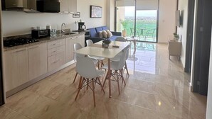 A modern kitchen with a dining area, a large window, and a view of the outdoors. - Apartment for Rent in Valle Aurora 2 BDR 8 min from the Sea! (Playa del Carmen)