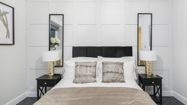 A hotel room with a large bed, two nightstands, and two wall-mounted mirrors. - Modern 1BR Flat | Walkable High Street Stay (Southend-on-Sea)