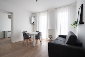 A modern living room with a dining area, a sofa, a table with chairs, and a white radiator. - Carducci Modern Apartment 7 by Wonderful Italy (Mestre)