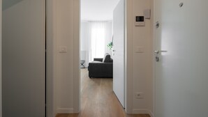 A hallway with a door leading to a living area with a sofa and a plant. - Carducci Modern Apartment 7 by Wonderful Italy (Mestre)