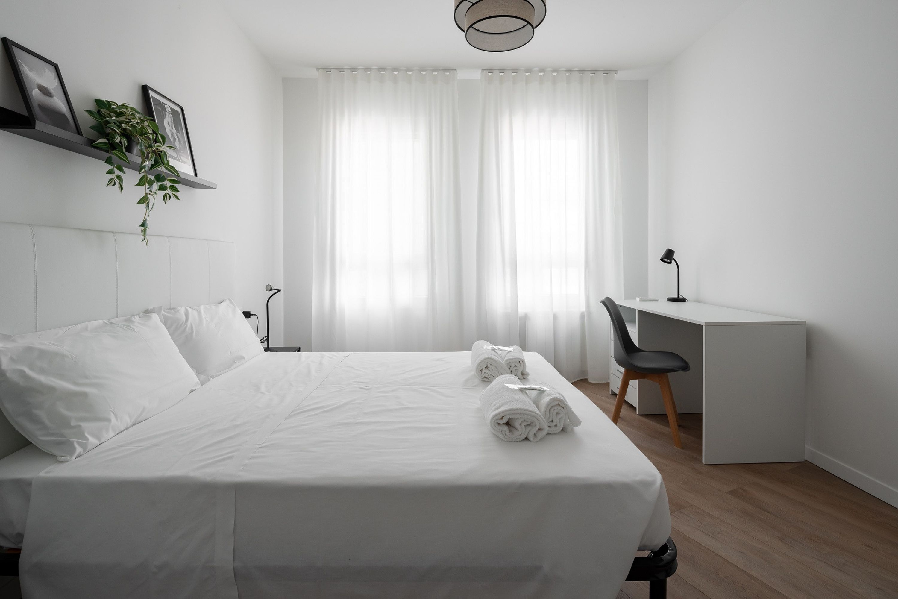 Una camera d'albergo dal design essenziale, con un letto rifatto, una scrivania e una sedia.