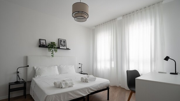 Un dormitorio moderno con cama, mesitas de noche, escritorio y silla.
