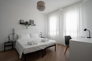 Une chambre à coucher moderne avec un lit, des tables de chevet, un bureau et une chaise.