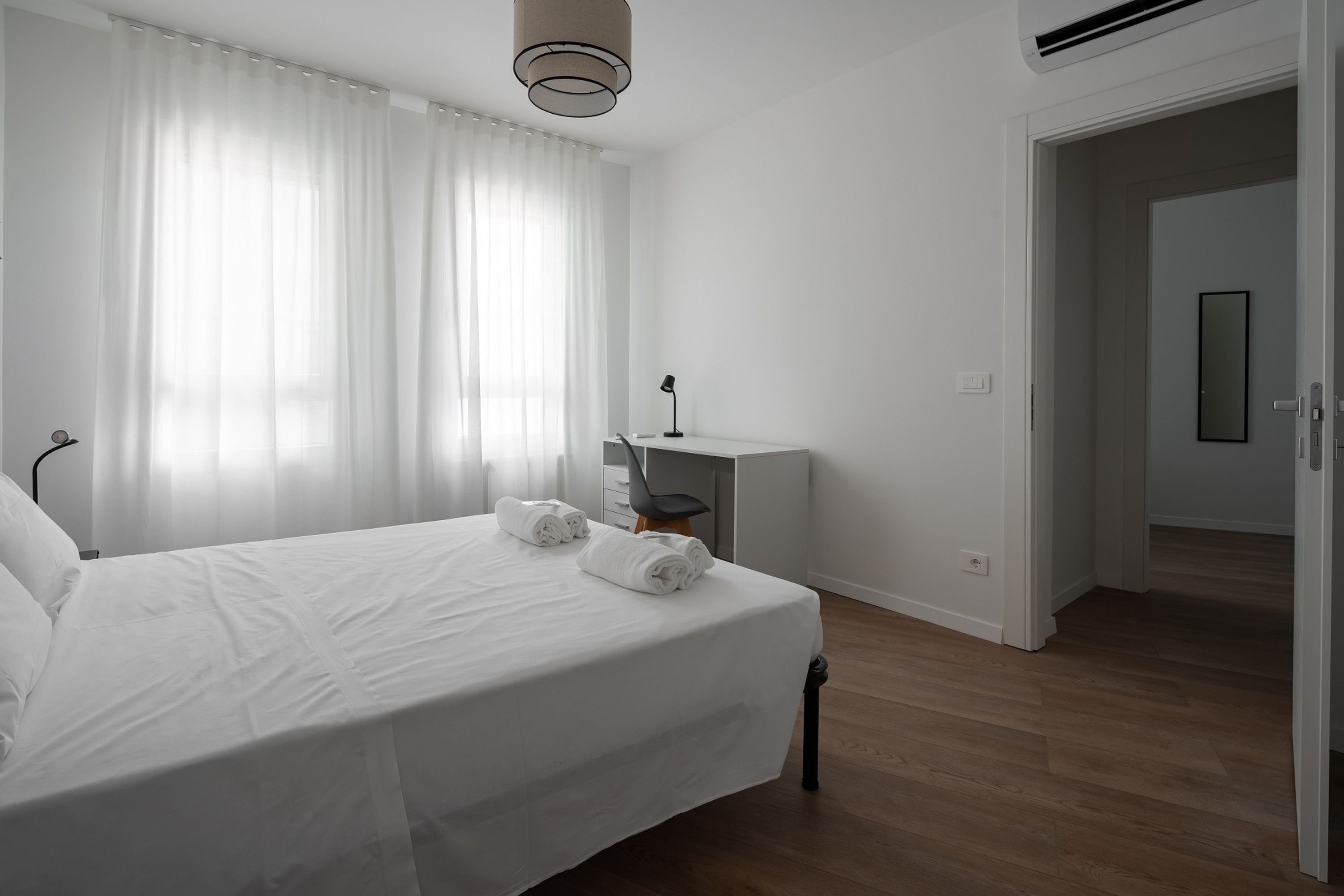 A bedroom with a bed, a desk, and a chair.