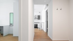 A modern, minimalist hallway with a wooden floor, white walls, and a kitchen area in the background. - Carducci Modern Apartment 1 by Wonderful Italy (Mestre)