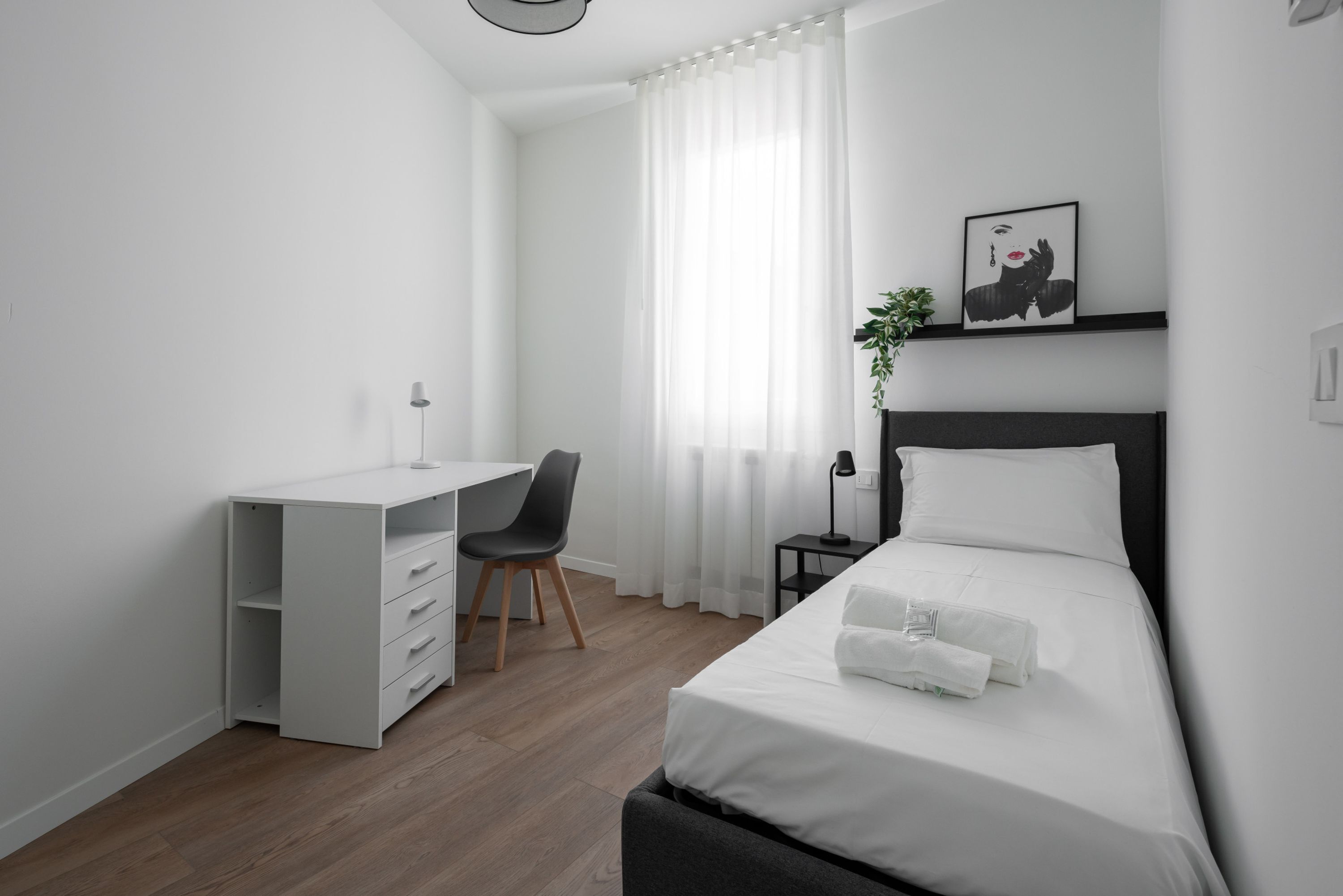 Ett modernt hotellrum med en säng, ett skrivbord och en stol.